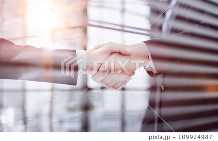 executives shaking hands in front of their manager and a colleague 109924987