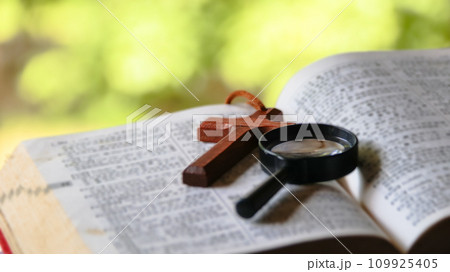 Black magnifying glass and brown wooden cross Black magnifying glass and brown wooden cross 109925405
