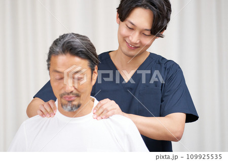 高齢男性の肩を揉む若い整体師 109925535