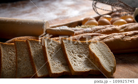 A Bakery Delight ingredient with sliced bread and loaf with wooden knead, egg 109925745