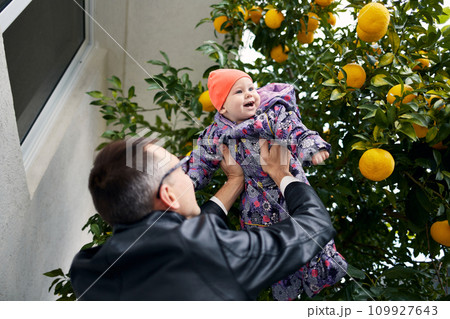 A young father lifts his little daughter above his head. A young father lifts his little daughter above his head. 109927643