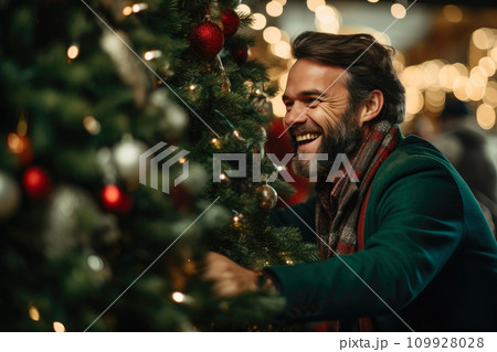 Cheerful Man Adding Sparkle to Christmas Tree 109928028