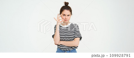 Young woman with doubtful face, zips her lips, seals mouth, promise not to tell anyone, isolated over white background Young woman with doubtful face, zips her lips, seals mouth, promise not to tell anyone, isolated over white background 109928791