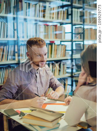 Classmates studying together in library Classmates studying together in library 109929775