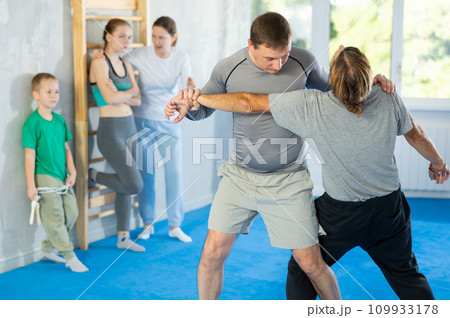 Man with trainer in self-defense training in gym practices trip up opponent during sparring 109933178