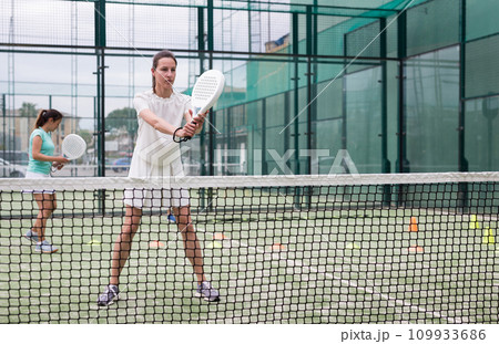 Focused woman and man learning to play padel on court 109933686