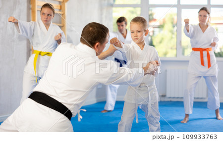 Teacher corrects boy pupil pose posture position of body, hands, legs during karate classes 109933763