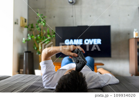 自宅でテレビゲームをする男性 109934020