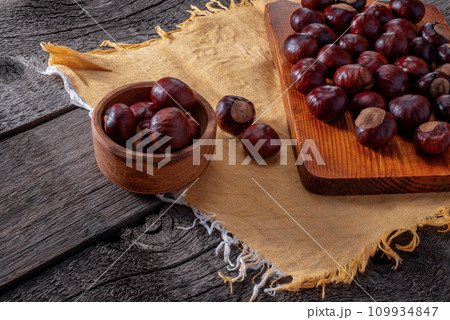 Chestnut in Wooden Plate and on Wooden Kitchen Board on Wooden Background. 109934847