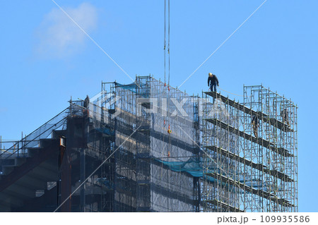 とび職 タワークレーンで足場組立工事の作業風景 とび職 タワークレーンで足場組立工事の作業風景 109935586