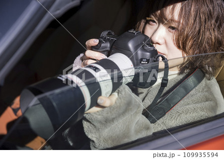 車内でカメラを持って張り込む若い女性記者 109935594