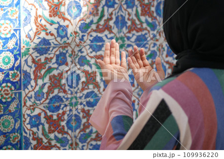 Muslim young woman in hijab is praying in mosque. Muslim young woman in hijab is praying in mosque. 109936220