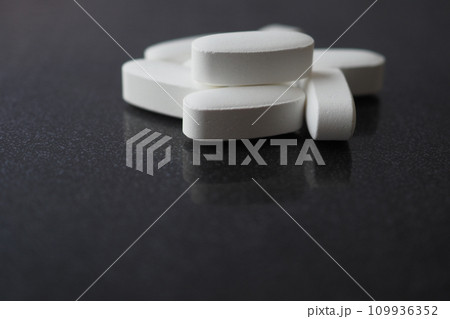 white color medical pills spilling on black  109936352