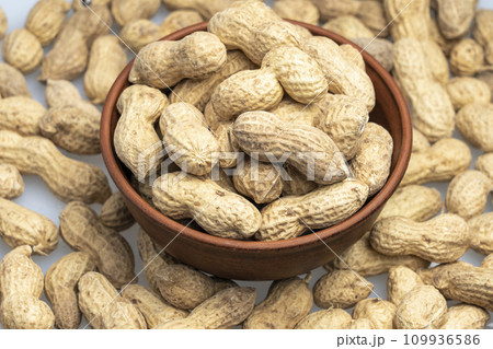 peanuts in a shell in a clay plate, organic peanuts isolated on a white background top view. A bunch of peanuts in close-up, selective focus. 109936586