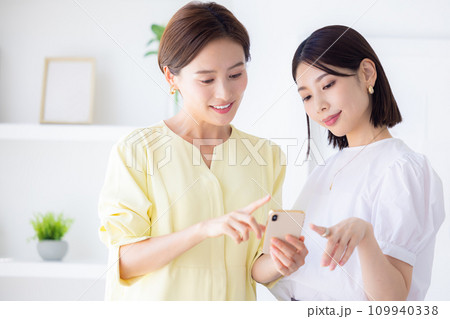 ビジネス スマホを見ながら相談する女性 ビジネス スマホを見ながら相談する女性 109940338
