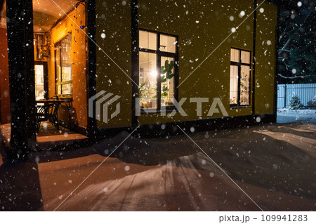 Cozy festive window of the house outside with the warm light of fairy lights garlands inside - celebrate Christmas and New Year in a warm home. Christmas tree, bokeh, snow on pine trees and snowfall Cozy festive window of the house outside with the warm light of fairy lights garlands inside - celebrate Christmas and New Year in a warm home. Christmas tree, bokeh, snow on pine trees and snowfall 109941283