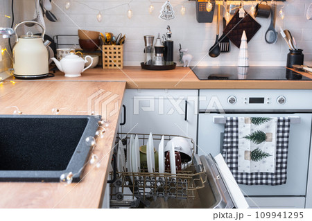 A lot of dirty dishes in the dishwasher in the festive kitchen. Helping the hostess, economy and ecology. Cleaning in the kitchen for the holidays of Christmas and New Year, after the feast and guests 109941295
