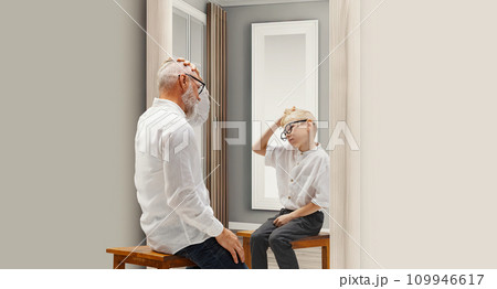 Years ago. Senior man sitting ear mirror with reflection of him as a child. Conceptual collage. Age, past and present, generation Years ago. Senior man sitting ear mirror with reflection of him as a child. Conceptual collage. Age, past and present, generation 109946617