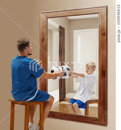 Man in uniform sitting with football ball in uniform and looking at his reflection as a child. Through ages. Conceptual collage. Age, past and present, generation 109946618