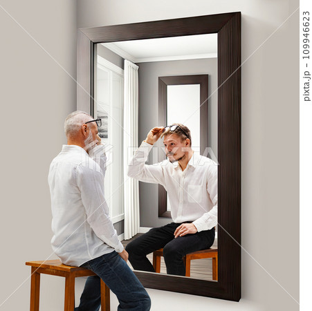 Revealing past memories. Senior man looking in mirror at his younger reflection. Through ages. Conceptual collage. Age, past and present, generation Revealing past memories. Senior man looking in mirror at his younger reflection. Through ages. Conceptual collage. Age, past and present, generation 109946623