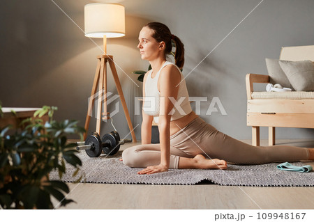 Active aerobics at home. Stretching in sportswear. Weight workout for fitness. Sporty woman in sportswear doing fitness stretching exercises at home in the living room 109948167