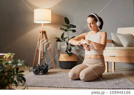 Athlete's smartwatch use. Female workout device. Healthy lifestyle tech. Wristwatch for health. Heart rate in fitness. Caucasian woman checking her workout time at home Athlete's smartwatch use. Female workout device. Healthy lifestyle tech. Wristwatch for health. Heart rate in fitness. Caucasian woman checking her workout time at home 109948186
