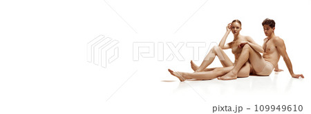 Banner. Attractive naked couple sitting on floor and posing against white studio background with negative space to insert text. Banner. Attractive naked couple sitting on floor and posing against white studio background with negative space to insert text. 109949610