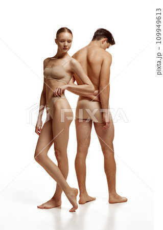 Body size portrait of naked couple, woman and man with perfect body shapes posing in beige underwear against white studio background. Body size portrait of naked couple, woman and man with perfect body shapes posing in beige underwear against white studio background. 109949613