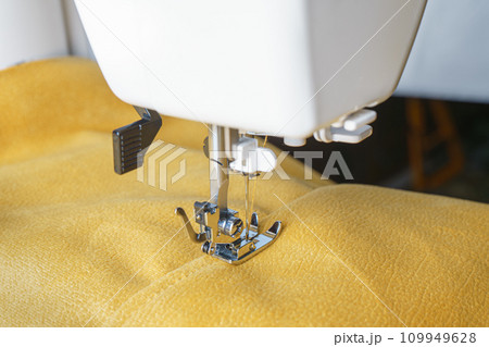 Modern sewing machine with yellow velours fabric close up 109949628