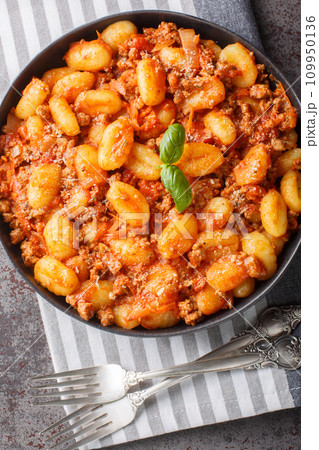Homemade potato gnocci served with classic meat Bolognese sauce close-up in a plate on the table. Vertical top view 109950136