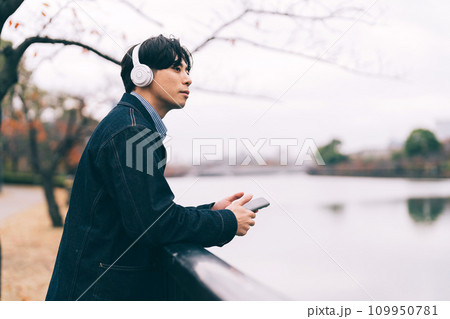 川沿いで音楽を聴く男性 109950781