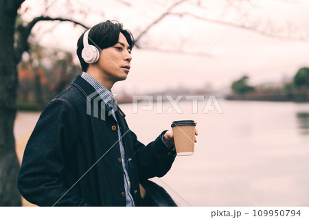 川沿いで音楽を聴く男性 109950794