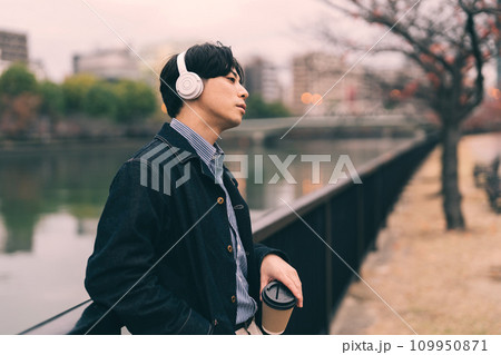 川沿いで音楽を聴く男性 川沿いで音楽を聴く男性 109950871