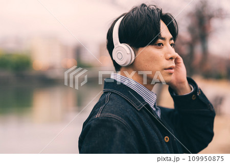 川沿いで音楽を聴く男性 109950875