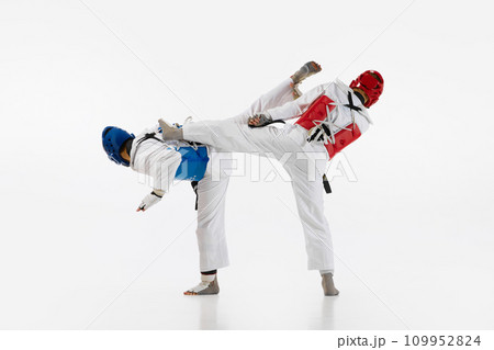 Competitive strong young men, taekwondo, karate athletes in motion, fighting, training isolated over white background. Martial arts, combat sport 109952824
