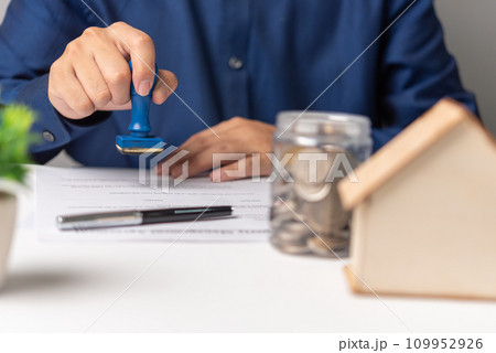 real estate agent with house. Business person holding a rubber stamping approved on mortgage loan contract agreement document house plan on the table. real estate agent with house. Business person holding a rubber stamping approved on mortgage loan contract agreement document house plan on the table. 109952926