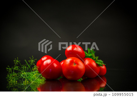 Ripe red tomatoes with greens on black background. Ripe red tomatoes with greens on black background. 109955015