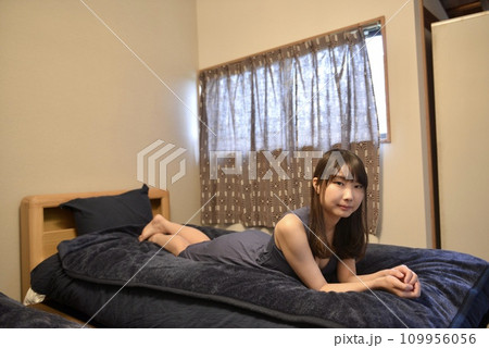 ベッドの上でくつろぐワンピース姿の若い女性 109956056