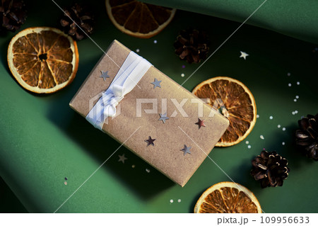 Christmas gift in craft paper on a green background. Christmas gift in craft paper on a green background. 109956633