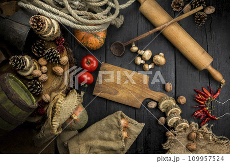 Rustic kitchen table with cutting board, kitchen utensils, vegetables and decoration. Copy space, add object or text. Top view image 109957524
