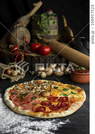 Italian Pizza Four Seasons (Pizza Quattro Stagioni) with different ingredients on the wooden table in the kitchen Italian Pizza Four Seasons (Pizza Quattro Stagioni) with different ingredients on the wooden table in the kitchen 109957528