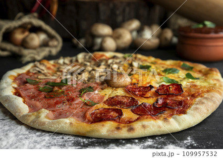 Italian Pizza Four Seasons (Pizza Quattro Stagioni) with different ingredients on the wooden table in the kitchen Italian Pizza Four Seasons (Pizza Quattro Stagioni) with different ingredients on the wooden table in the kitchen 109957532