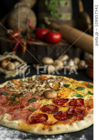 Italian Pizza Four Seasons (Pizza Quattro Stagioni) with different ingredients on the wooden table in the kitchen Italian Pizza Four Seasons (Pizza Quattro Stagioni) with different ingredients on the wooden table in the kitchen 109957541