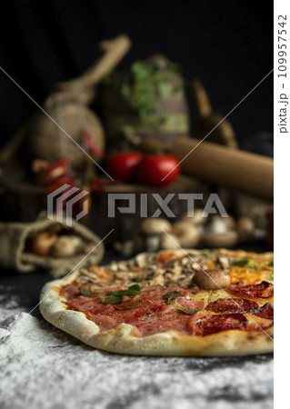 Italian Pizza Four Seasons (Pizza Quattro Stagioni) with different ingredients on the wooden table in the kitchen 109957542