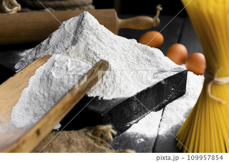 Pile of Flour with Spaghetti, eggs and vintage, rustic utensils in background. Selective focus on the Flour 109957854