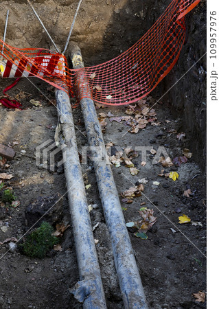 Pipeline reparation and reconstruction in the trench surrounded with orange safety net 109957976