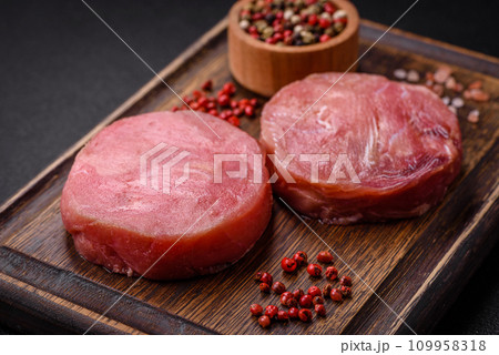 Round shape steaks of raw juicy tuna with salt and spices Round shape steaks of raw juicy tuna with salt and spices 109958318