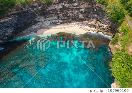 Cliff broken by wave of ocean formed perfect paradise untouched beach. Natural azure bathing pool in the rock. Angel's Billabong is popular tourist destination on island of Nusa Penida in Indonesia. 109960100