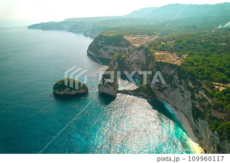 Cinematic aerial landscape shots of the beautiful island Diamond beach of Nusa Penida. Huge cliffs by the shoreline and hidden dream beaches with clear water. 109960117