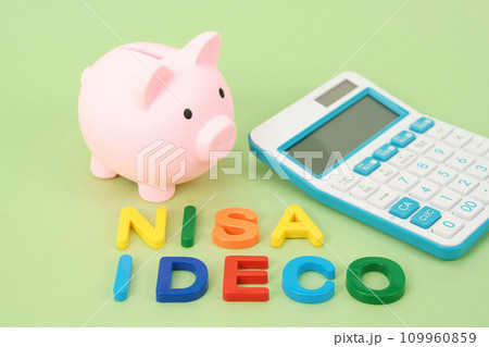 NISAとiDeCoイメージ　カラフルな文字とブタの貯金箱と電卓 109960859